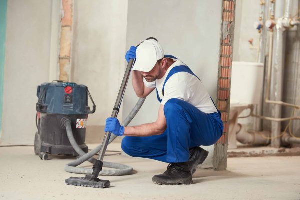 service man cleaning and removing construction dust with vacuum cleaner after repair